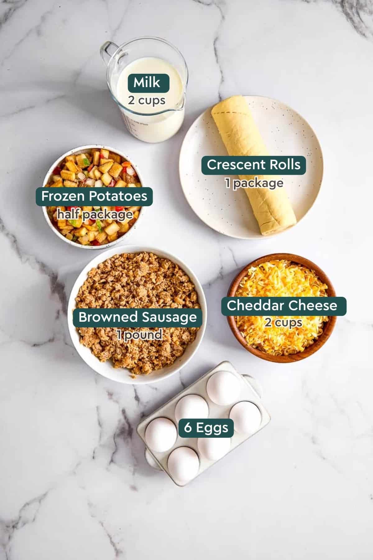 Ingredients for Christmas breakfast casserole, including milk, crescent rolls, frozen potatoes, sausage, cheese, and eggs.