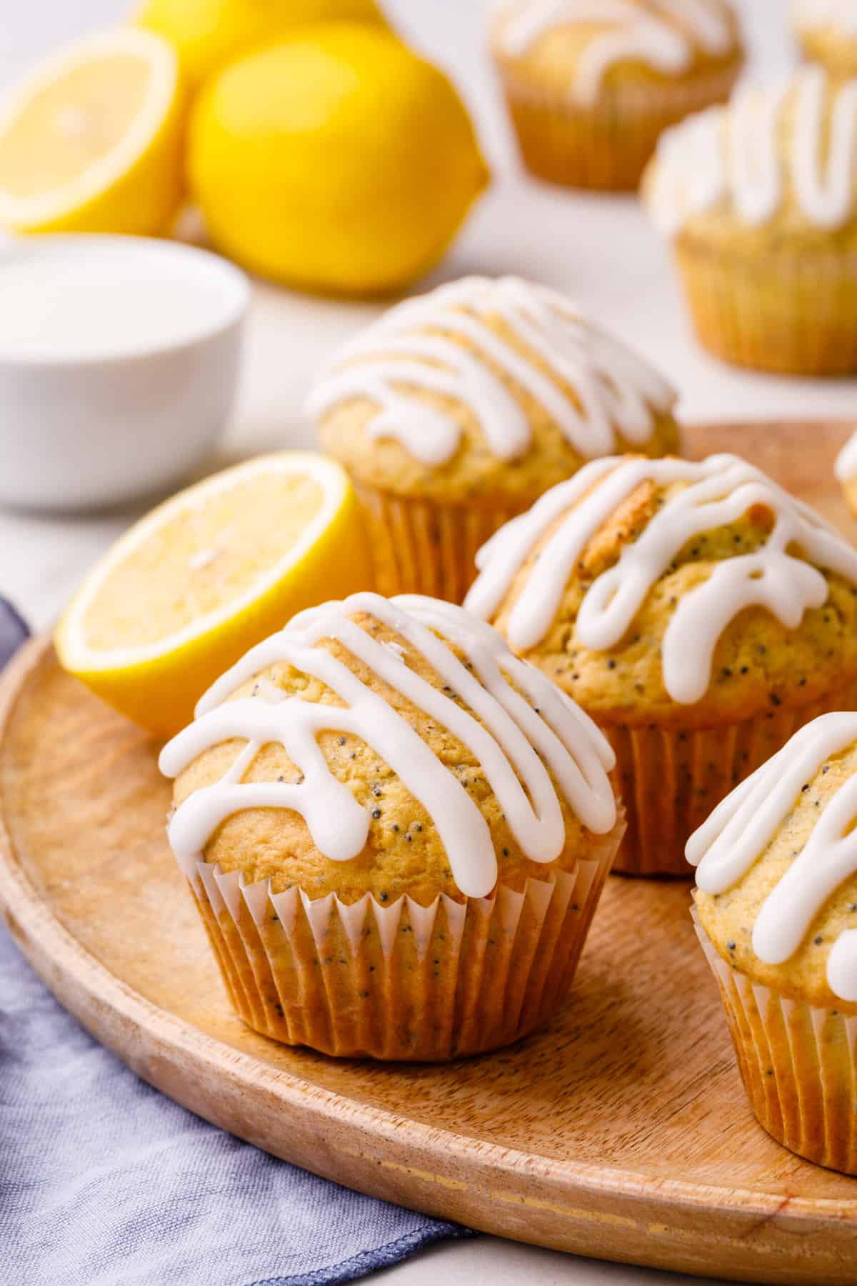 close up image of lemon poppy seed muffins topped with glaze served on a wooden plate