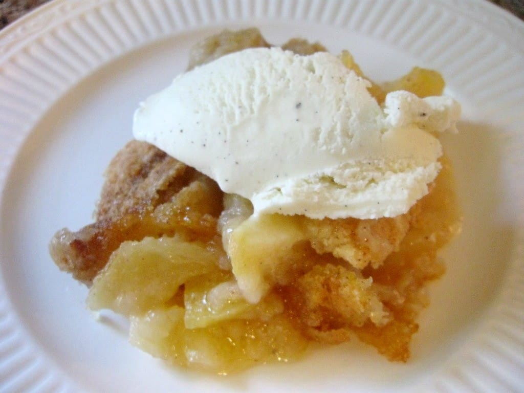 apple crisp on a plate and topped with ice cream
