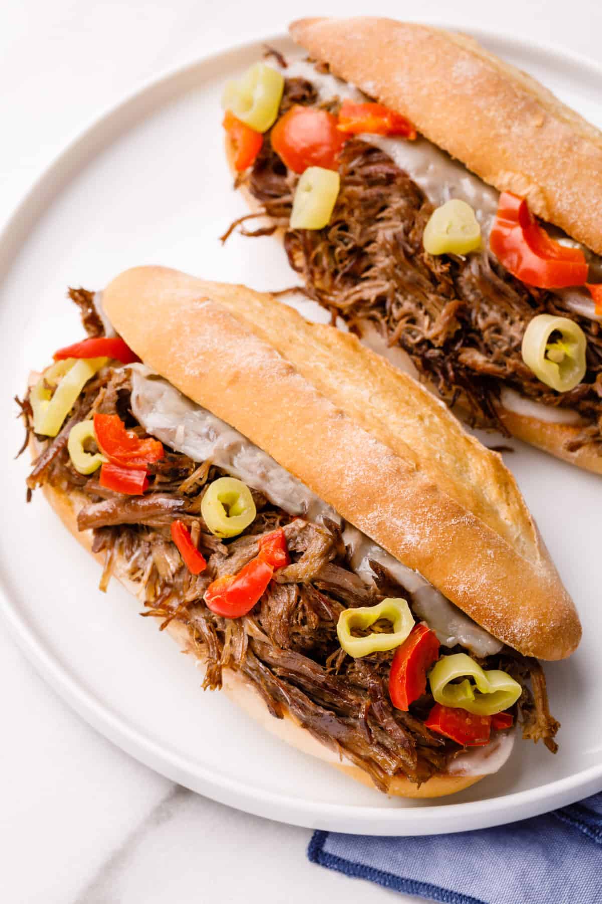 two italian beef sandwiches served on a white round plate
