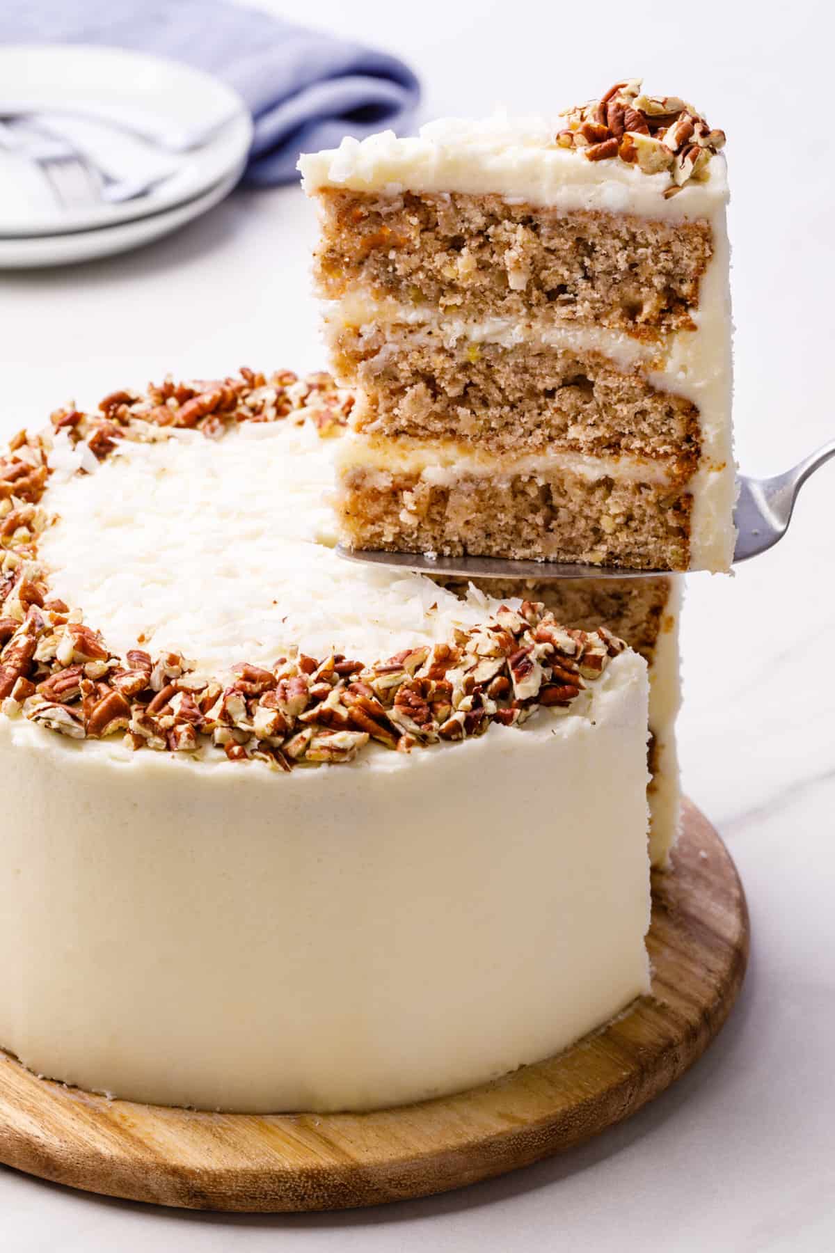 frosted hummingbird cake with a slice cut sitting on a cake spatula showing the cross section