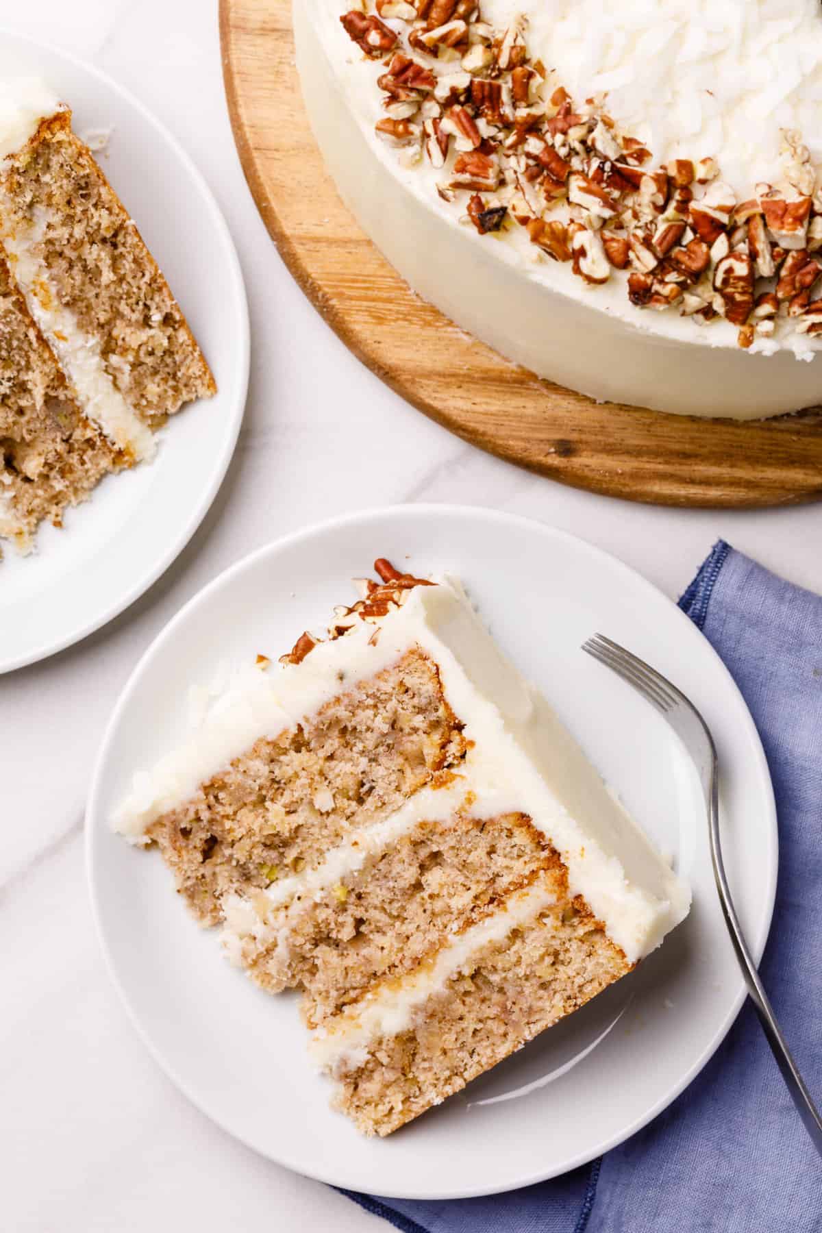 top down image of a slice of hummingbird cake served on a white round plate with a silver fork