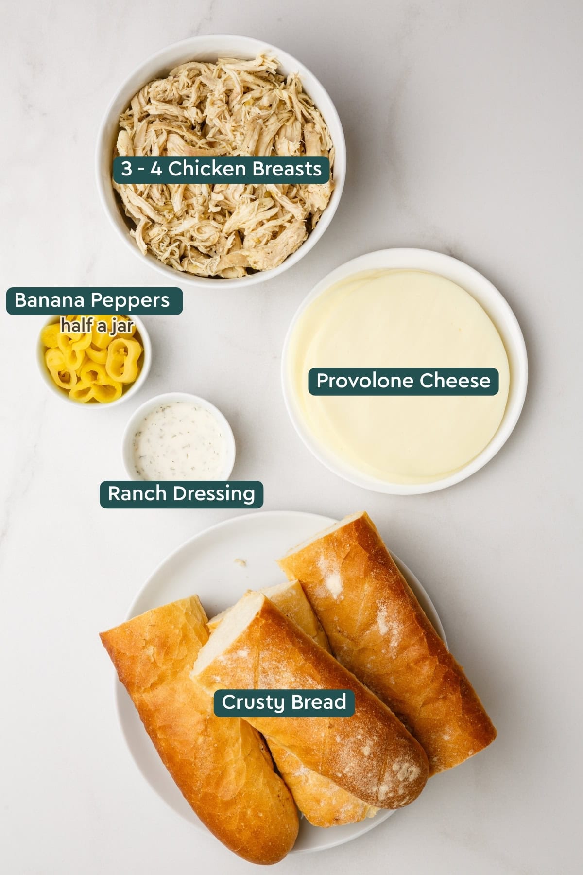 Ingredients for slow cooker Italian chicken sandwiches, including chicken, banana peppers, provolone, ranch, and bread.