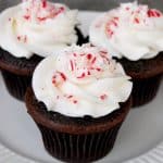 Three chocolate candy cane cupcakes on a plate.