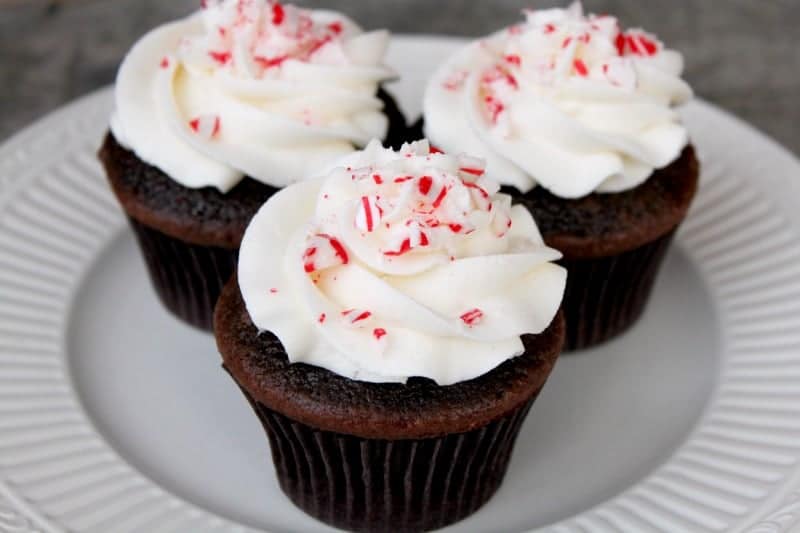 Three chocolate candy cane cupcakes on a plate.