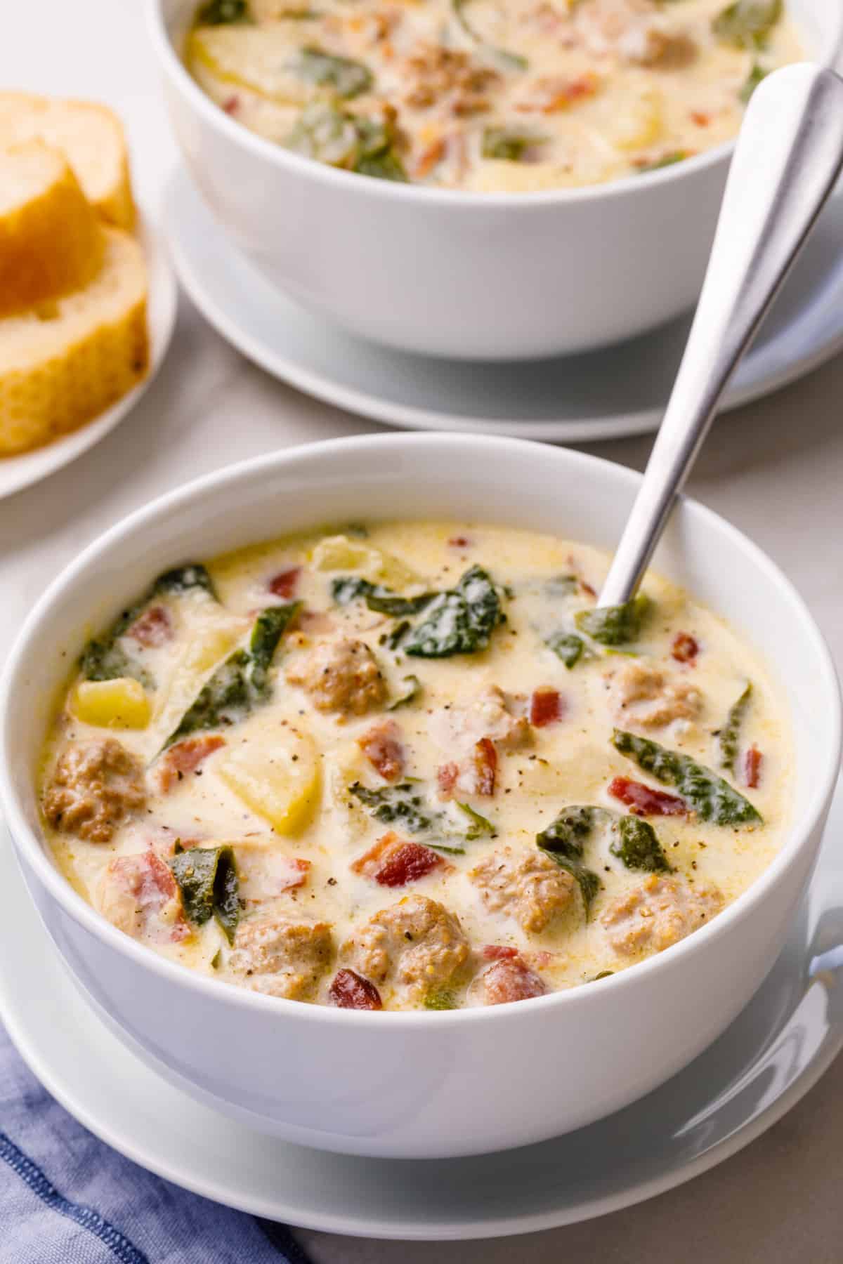 bowl of warm olive garden copycat recipe for zuppa toscana soup served in a white bowl with a silver spoon