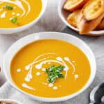 butternut squash soup with sour cream and cilantro served in a white bowl