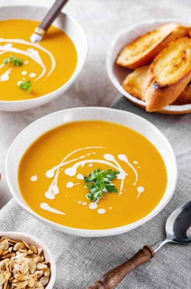 butternut squash soup with sour cream and cilantro served in a white bowl
