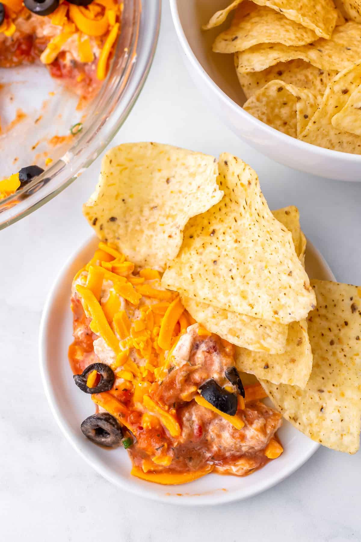 four layer fiesta dip served in a bowl with tortilla chips