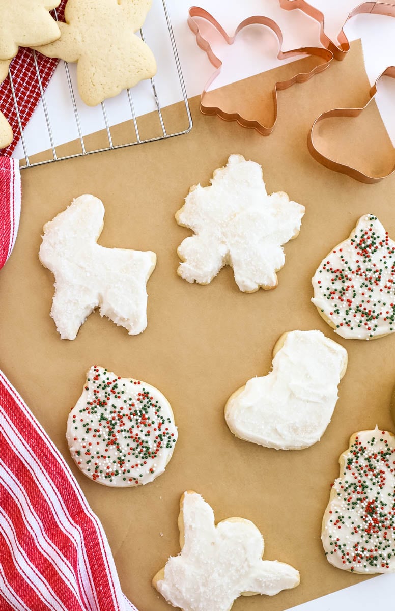 different christmas-shaped sugar cookies with white icing and green and red round sprinkles. 
