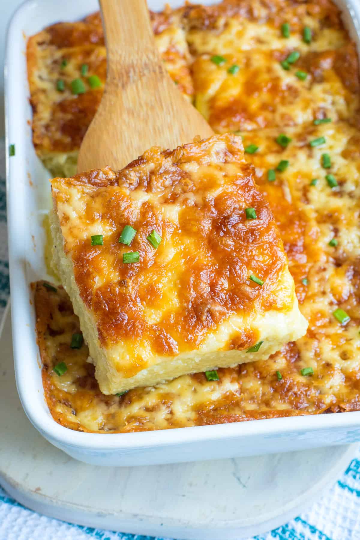 serving of cheesy egg and potatoes casserole sitting on a wood spatula