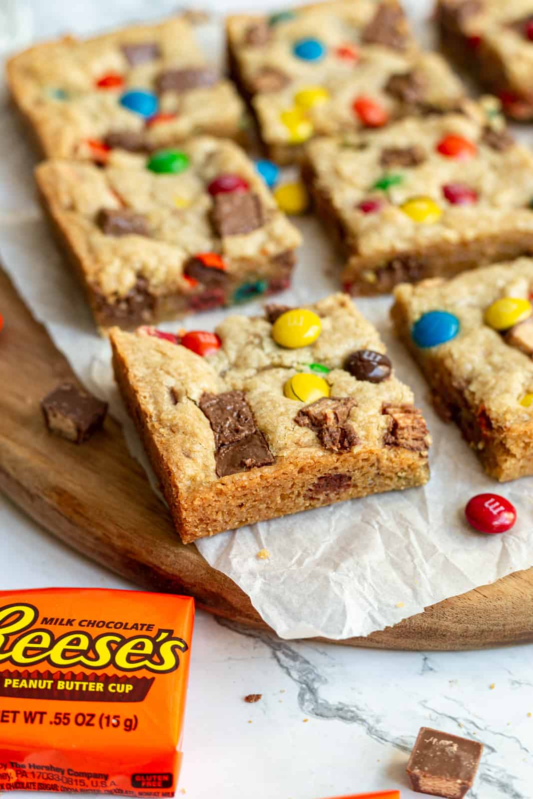 close up image of leftover halloween candy cookie bars cut into squares sitting on a wooden board