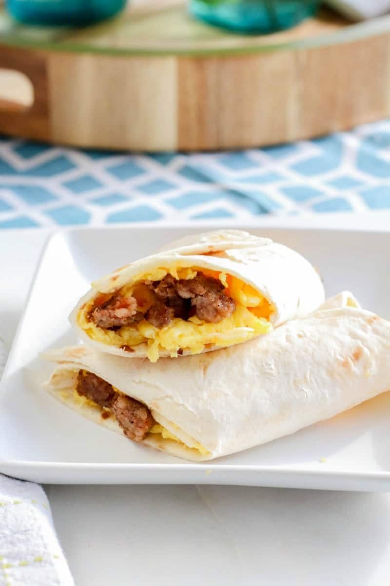 Make ahead freezer breakfast burrito cut in half and stacked on a plate