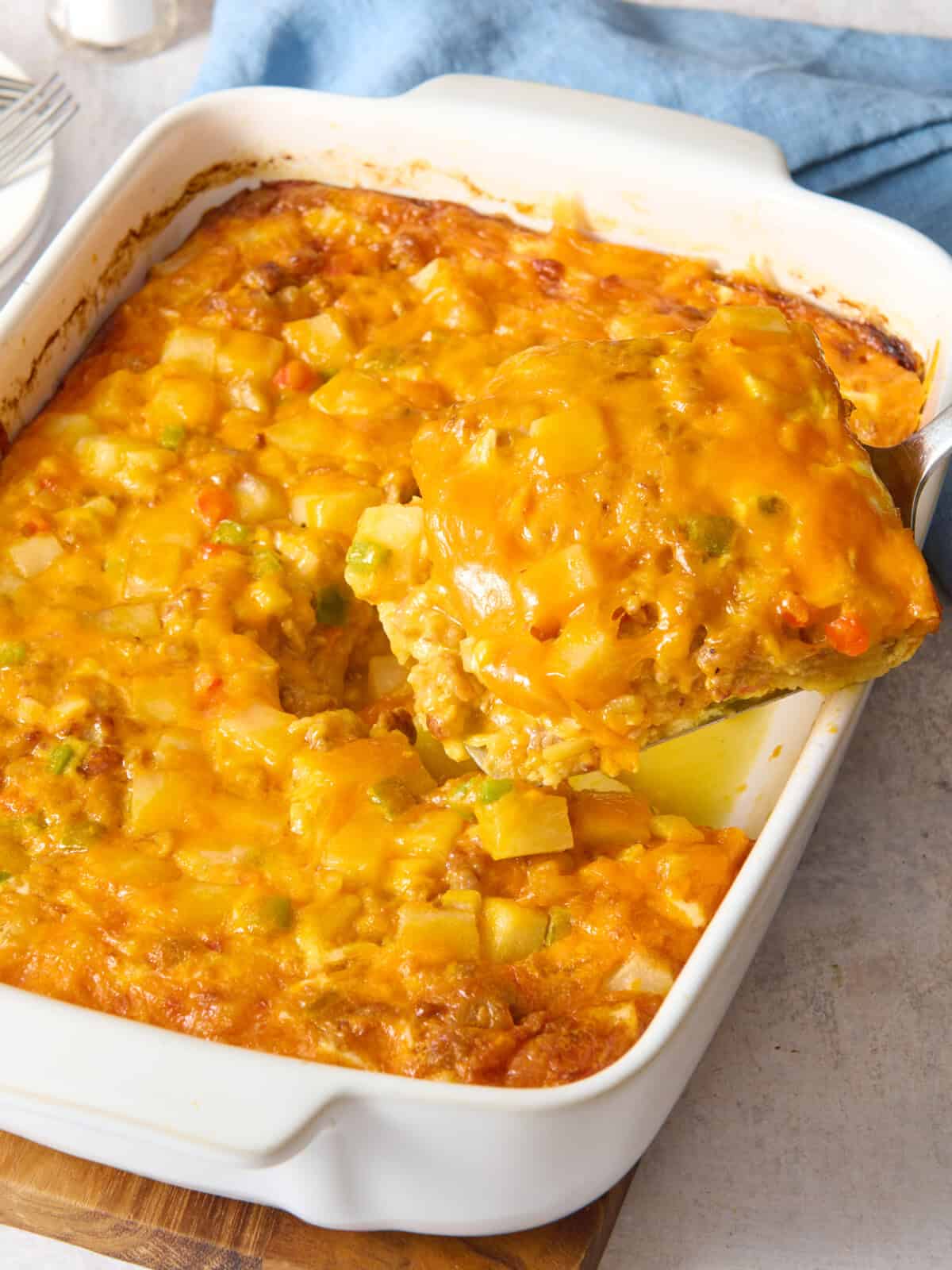 Overnight breakfast casserole in dish with portion on spatula.