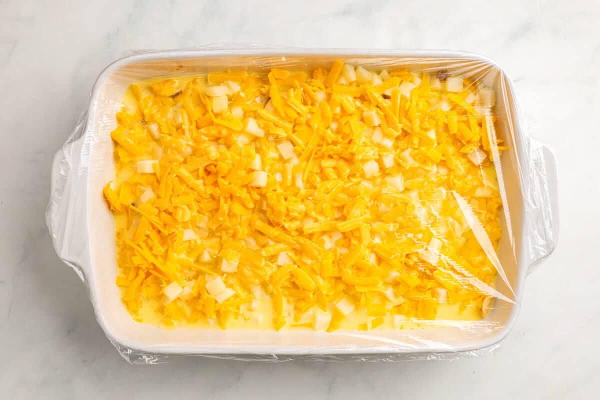 Plastic wrap covering dish with overnight breakfast casserole.