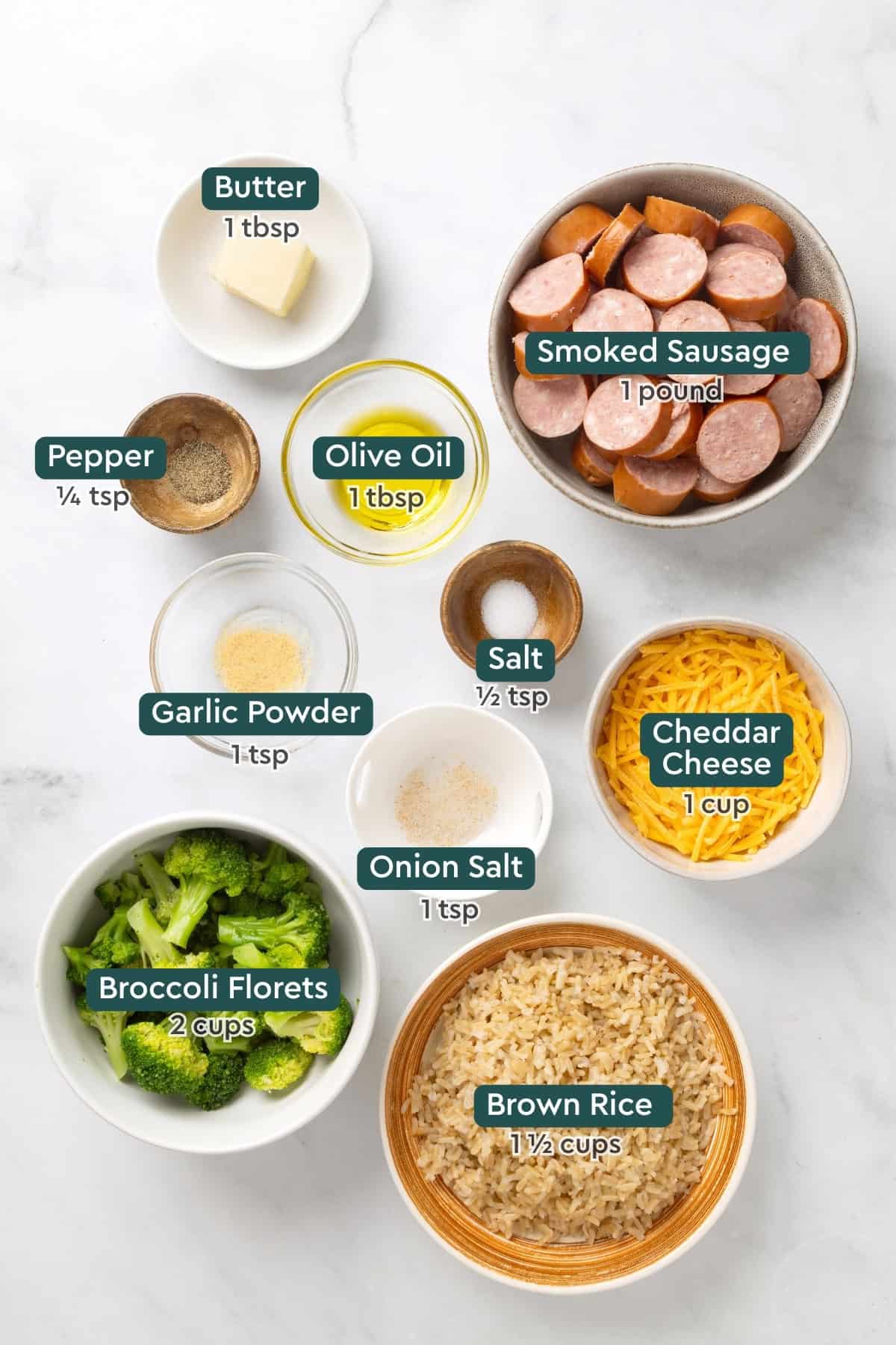 Ingredients for smoked sausage skillet, including sausage, butter, oil, salt, pepper, garlic powder, onion salt, cheddar, broccoli, and brown rice.