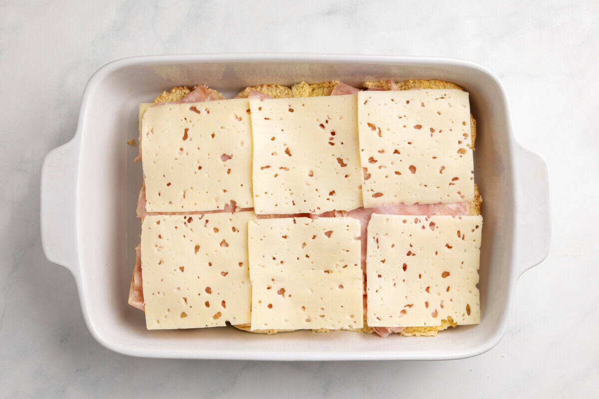 Swiss cheese added to baking dish of sliders.