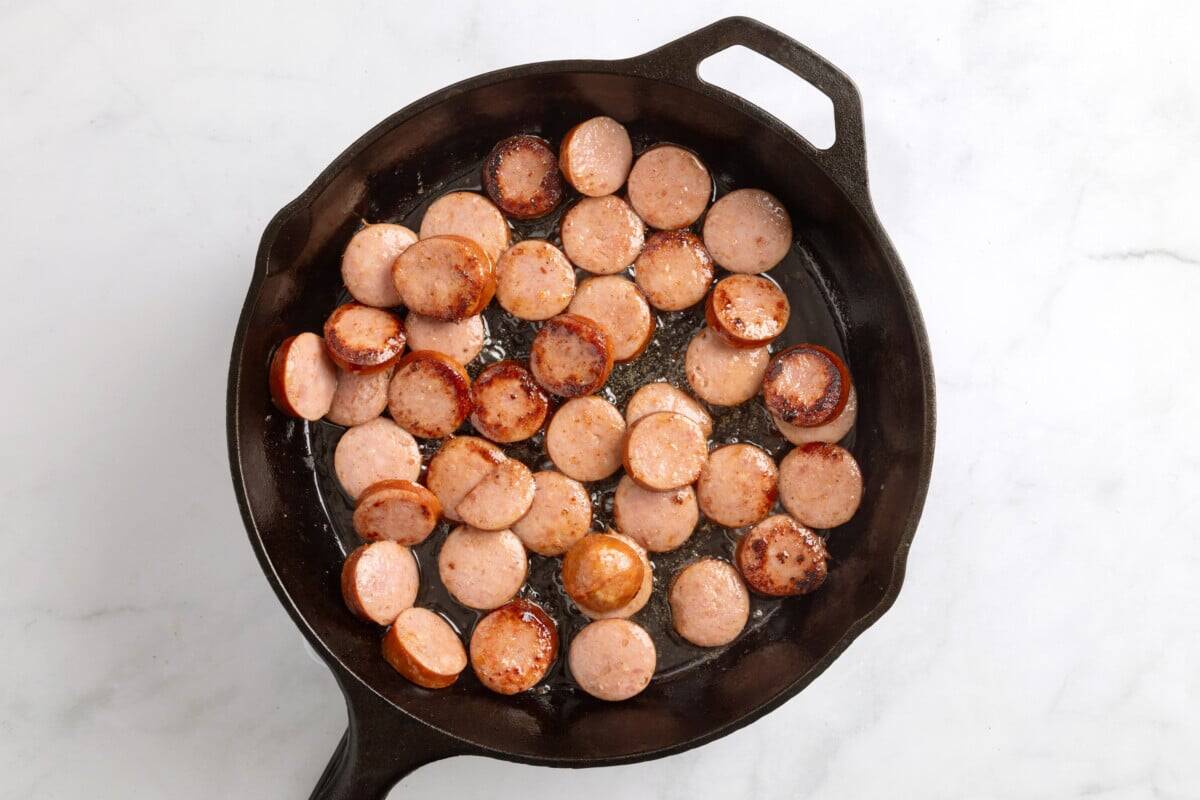 Browned smoked sausage in cast iron skillet.