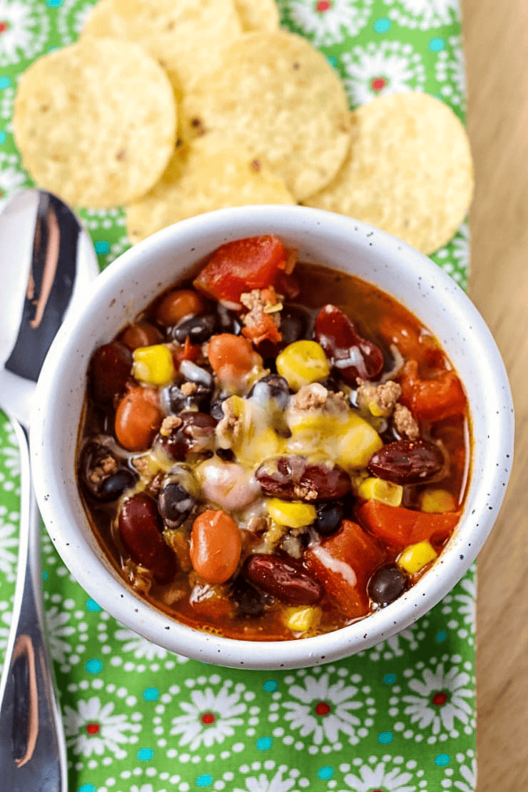 taco soup topped with melted cheese in a white bowl on a table