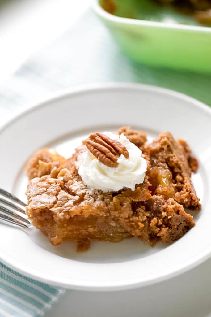 Apple Dump Cake Recipe topped with a little bit of whipped cream and a pecan