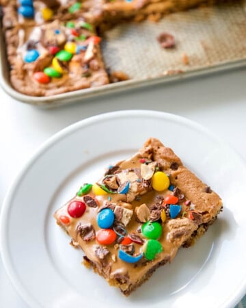 Skip all the hassle of measuring, mixing and scooping cookie dough and create this Chocolate Chip Candy Cookie Bar.  With all the fun flavors of a chocolate chip cookie with loads of candy bar toppings and peanut butter, make these Chocolate Chip Cookie Bars exceptionally special! #chocolatechipcookiebars #chocolatechipcookies #chocolate #cookies #peanutbutter | allthingsmamma.com