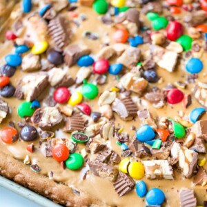 Skip all the hassle of measuring, mixing and scooping cookie dough and create this Chocolate Chip Candy Cookie Bar. With all the fun flavors of a chocolate chip cookie with loads of candy bar toppings and peanut butter, make these Chocolate Chip Cookie Bars exceptionally special! #chocolatechipcookiebars #chocolatechipcookies #chocolate #cookies #peanutbutter | allthingsmamma.com