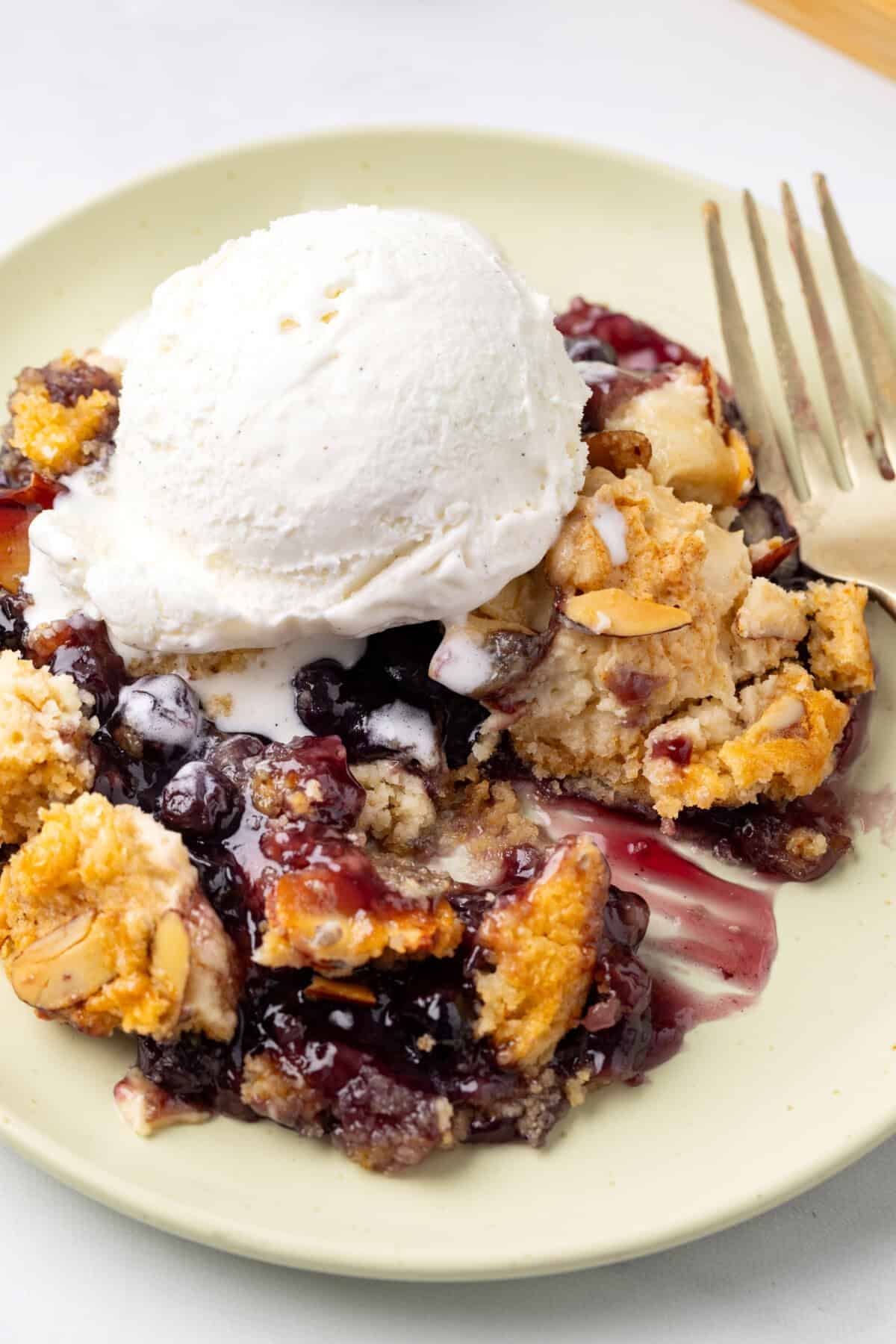 Plate with blueberry dump cake and scoop of ice cream.