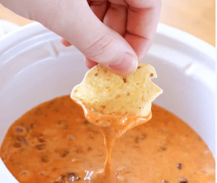hand dipping a chip into the dip 