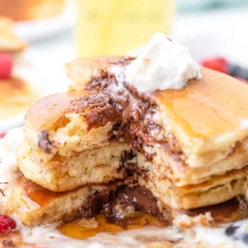 A stack of Nutella stuffed pancakes with a bite missing.