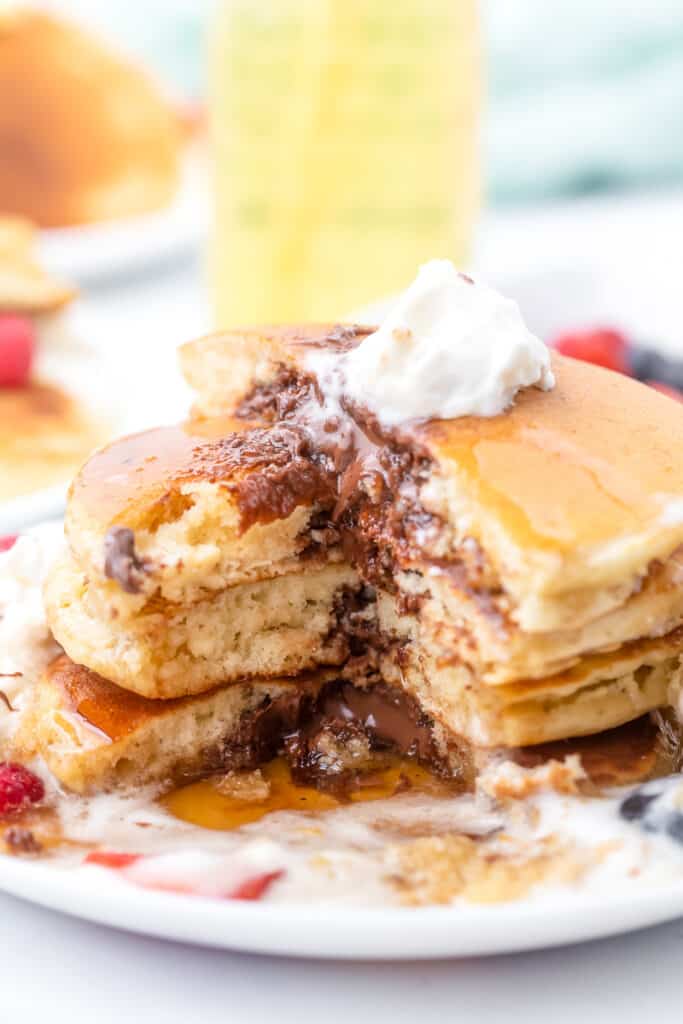 A stack of Nutella stuffed pancakes with a bite missing.