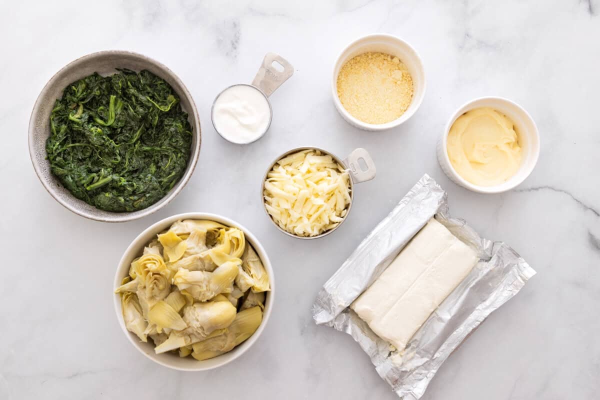 Ingredients for spinach artichoke dip, including frozen spinach, artichokes, mozzarella, parmesan, mayo, cream cheese, sour cream.