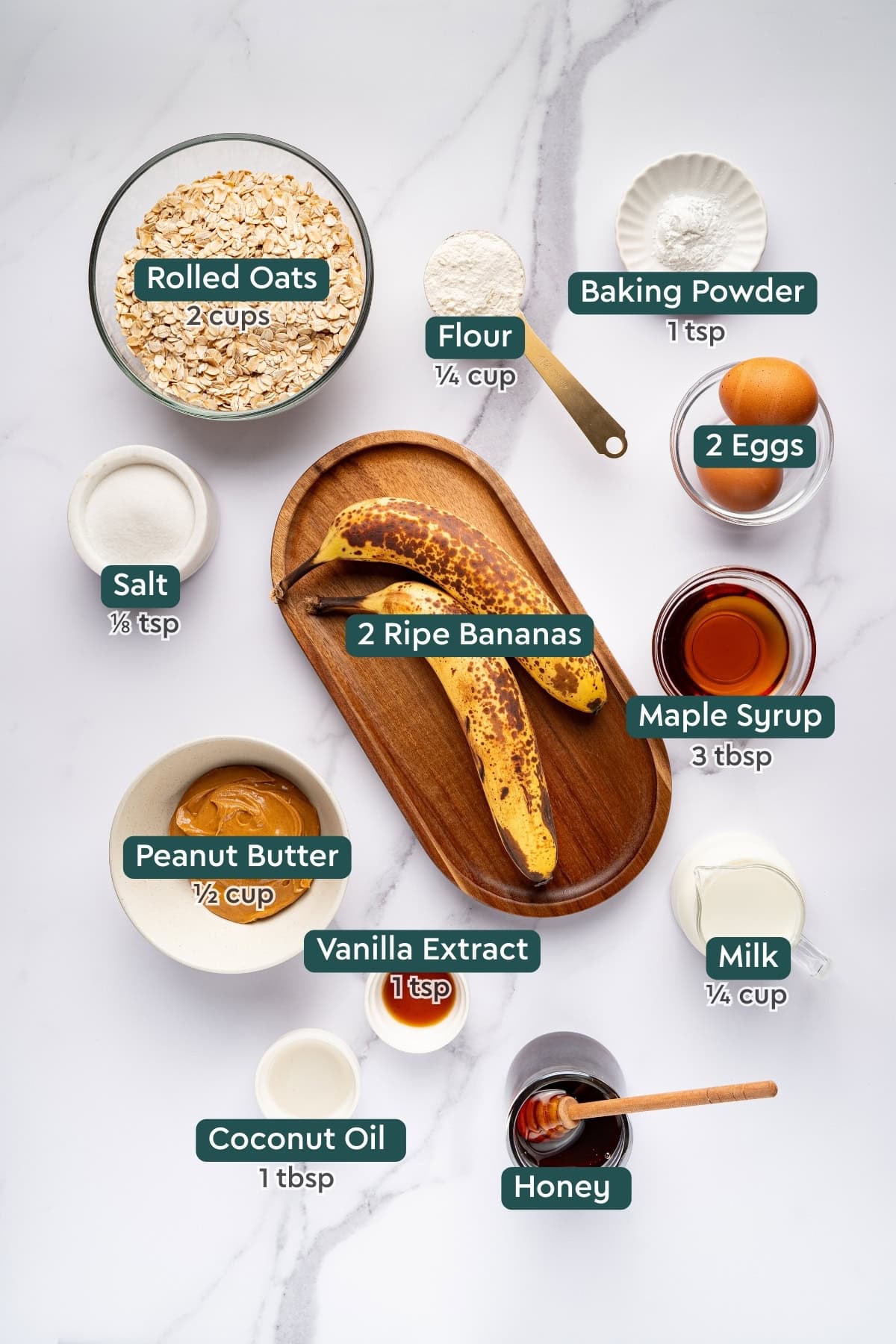 Ingredients for peanut butter banana oatmeal bars, including oats, baking powder, flour, eggs, salt, banana, maple syrup, peanut butter, vanilla, milk, coconut oil, and honey.