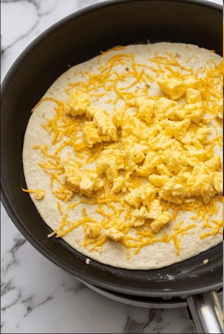 Scrambled eggs on tortilla with cheese.