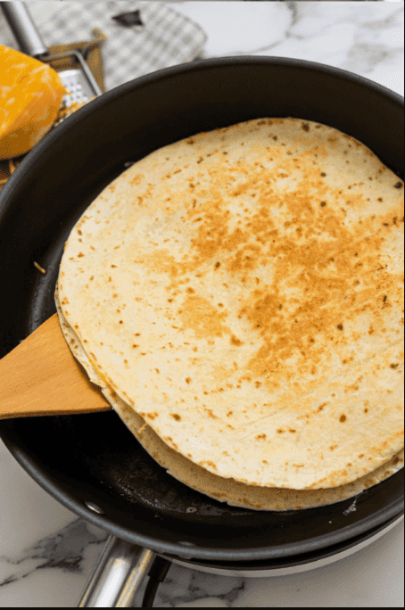 Spatula flipping breakfast quesadilla in pan.