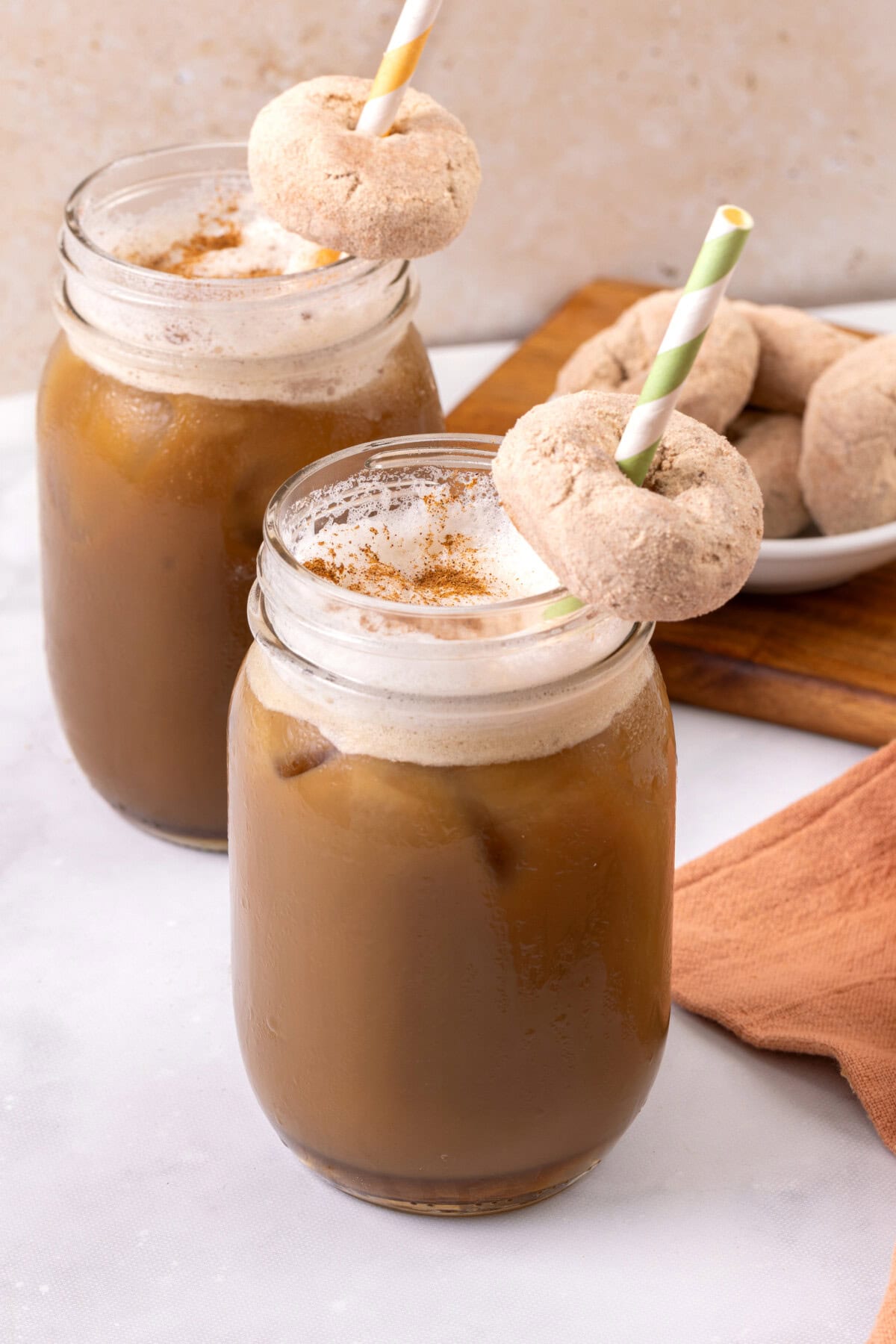 Mason jars filled with pumpkin spice cold brew, with donuts on straws.