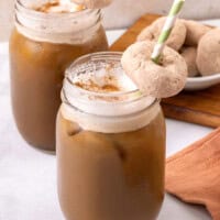 Mason jars filled with pumpkin spice cold brew, with donuts on straws.