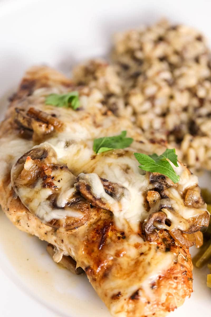 cheesy chicken with mushrooms  on a white plate 