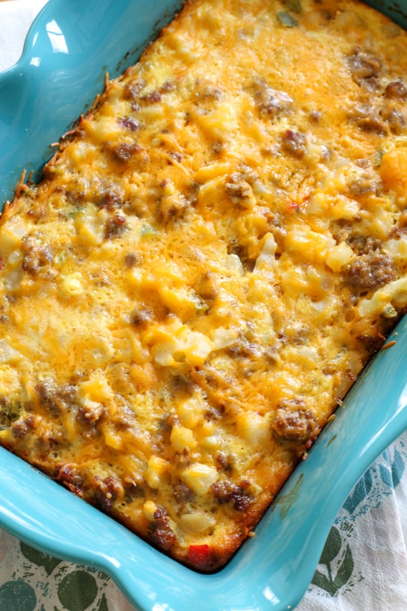 Breakfast casserole of eggs, hashbrowns and sausage topped with cheese in a blue ceramic pan