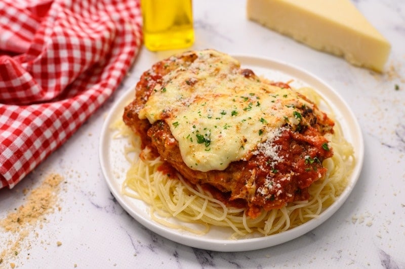 The Best Baked Chicken Parmesan recipe is made with breaded chicken cutlets that are browned on the stovetop and finished in the oven before being topped with marinara sauce and mozzarella cheese! The Best Baked Chicken Parmesan has a  crispy coating made with Italian breadcrumbs and grated parmesan cheese, smothered in a store-bought marinara sauce and sliced mozzarella cheese for an easy dinner any night of the week!