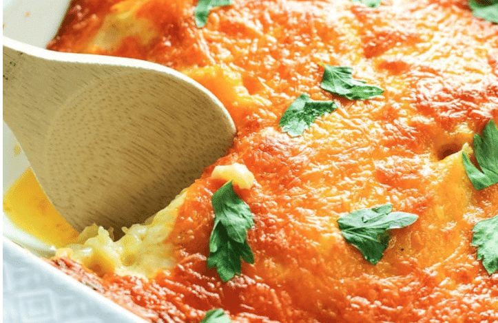 A wooden spoon dipping into a dish of scalloped potatoes. 