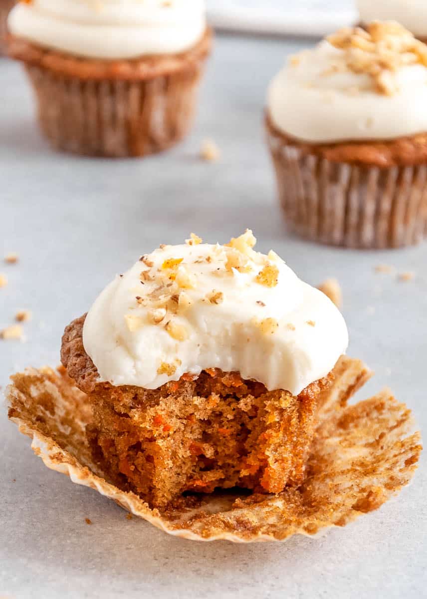 a bite taken out of a homemake carrot cake cupcake with cream cheese frosting