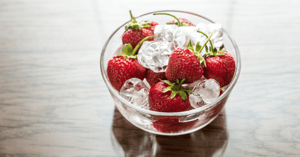 Fresh strawberries and ice cubes in a bowl.