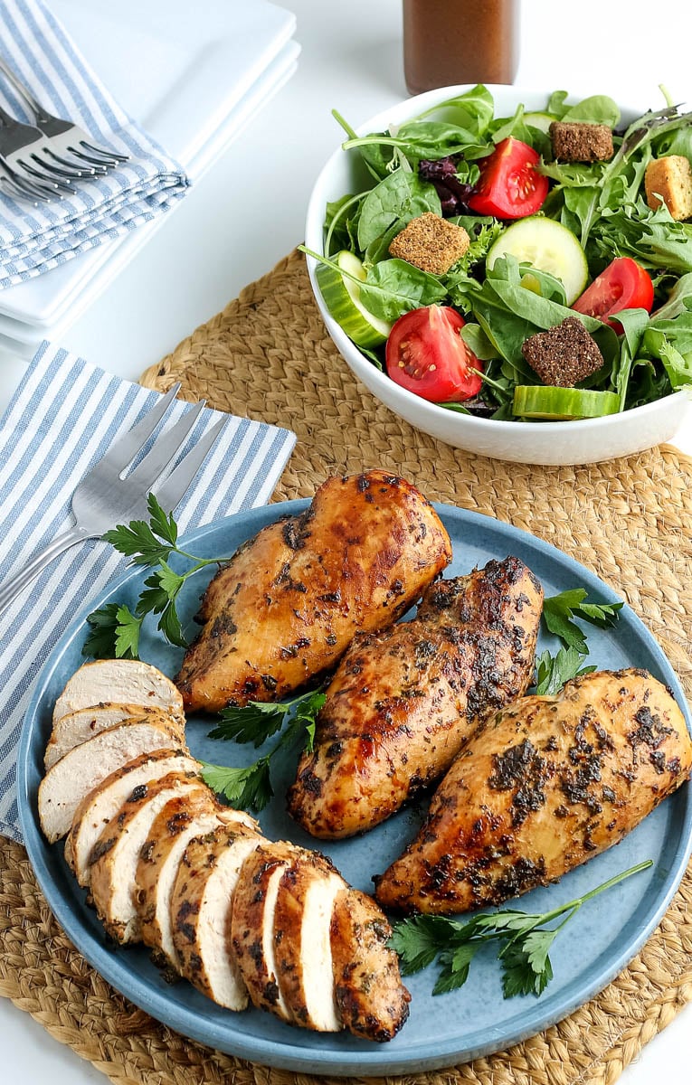 plate of whole chicken breasts and sliced chicken breasts with a side salad 