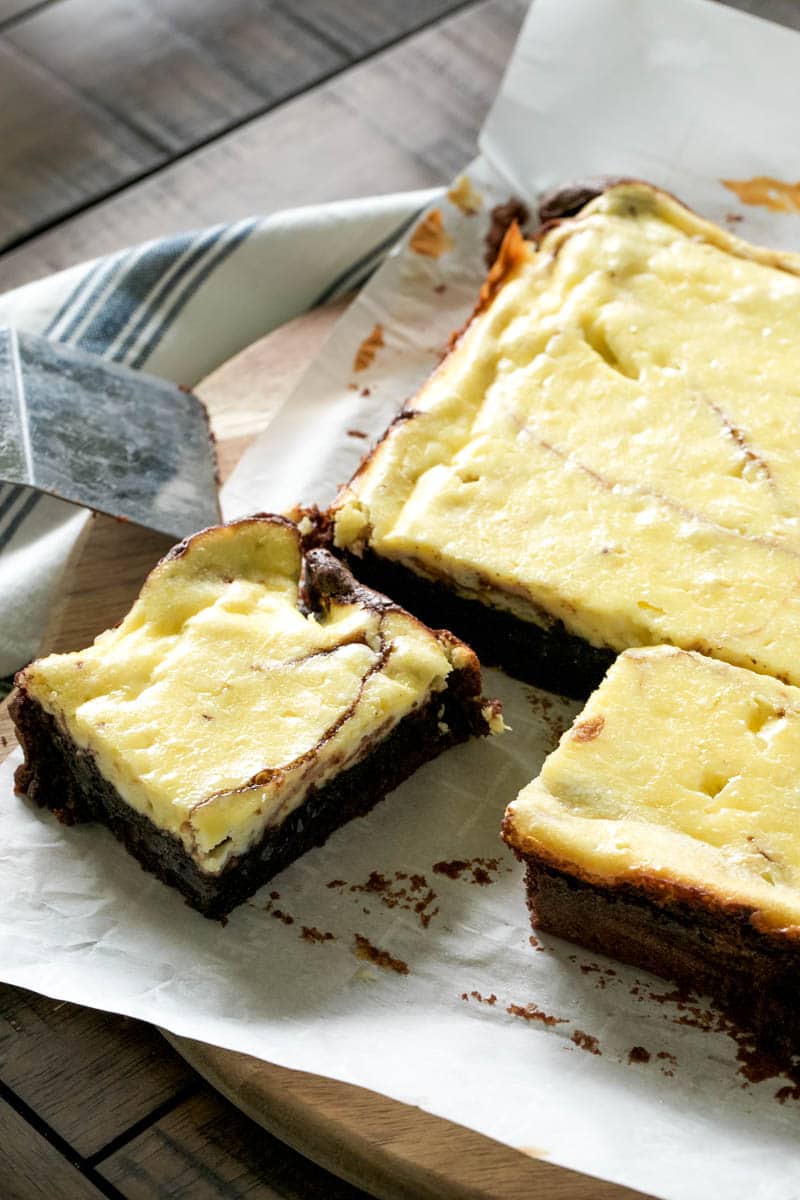 A cream cheese brownie being sliced from a slab of brownies. 