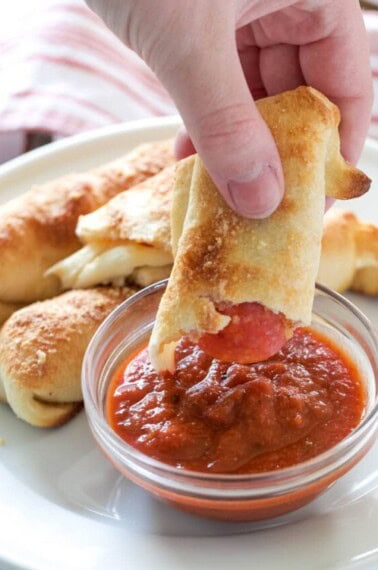 dipping pepperoni sticks into marinara sauce