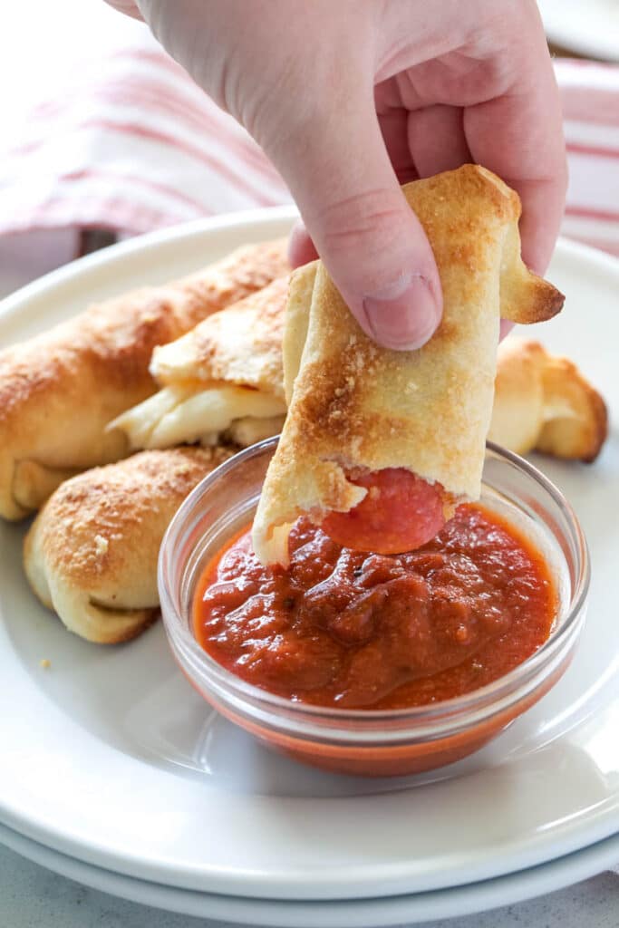 dipping pepperoni sticks into marinara sauce