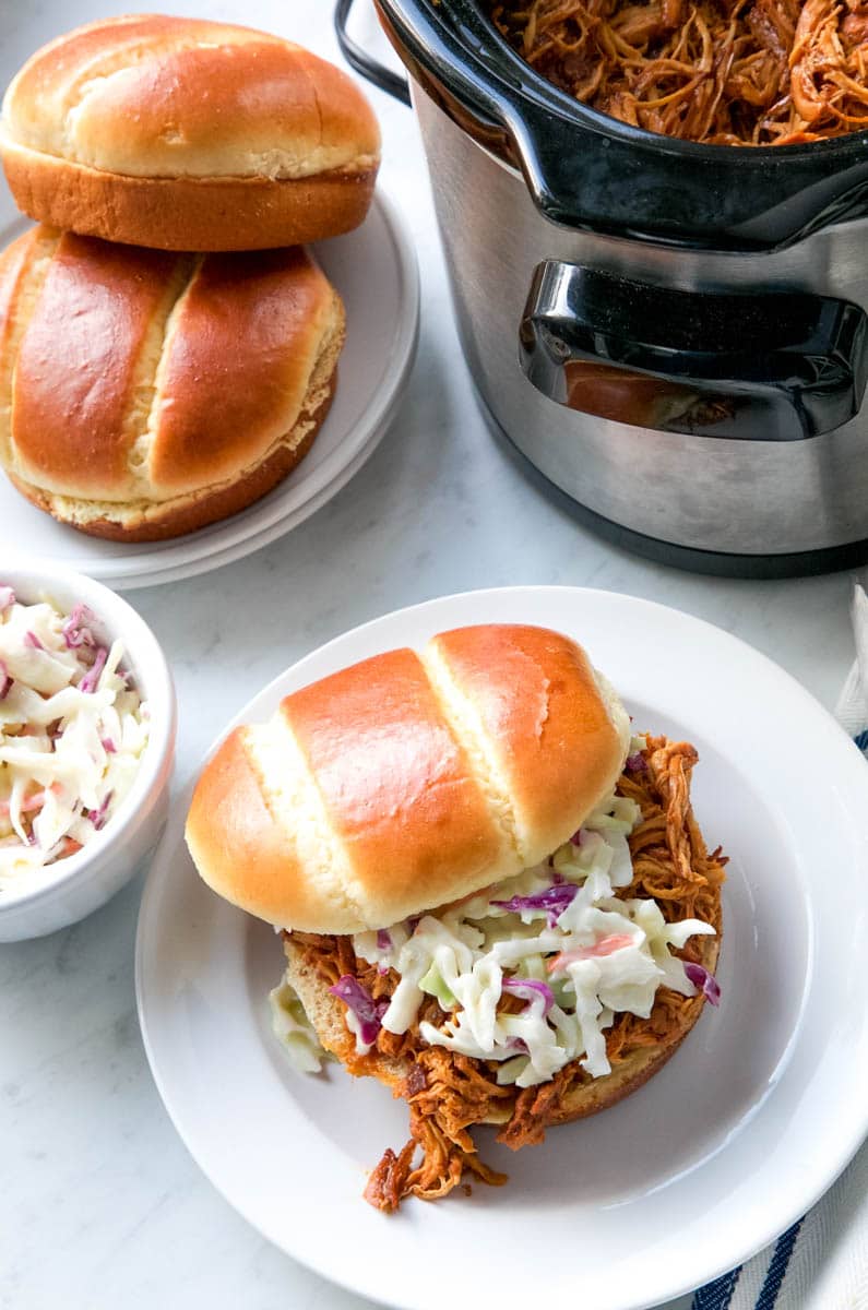 Plates of BBQ chicken sandwiches and coleslaw.