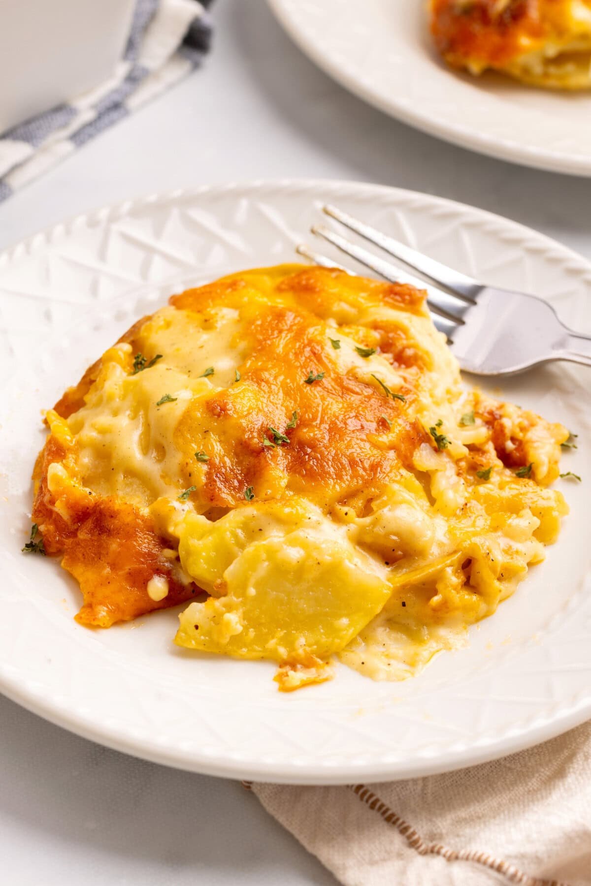 Plate of cheesy scalloped potatoes with fork.