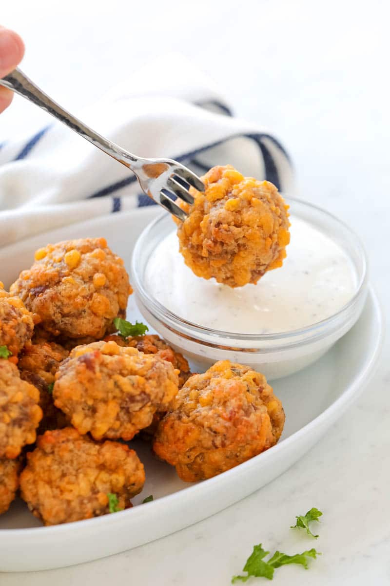 plate of sausage balls being dipped in ranch