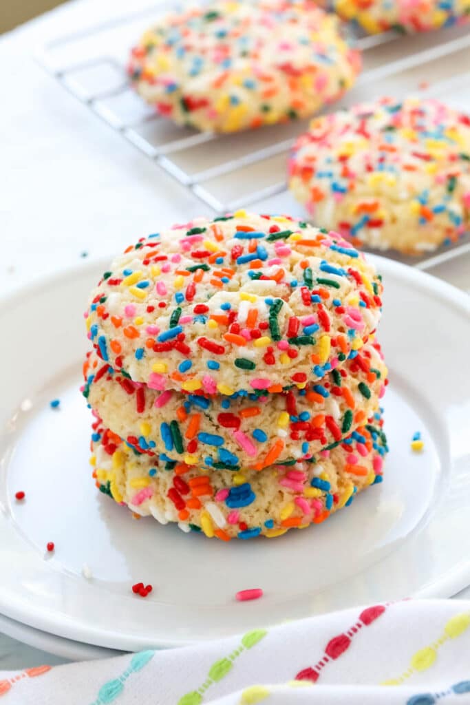Three Funfetti cake mix cookies stacked on a plate.